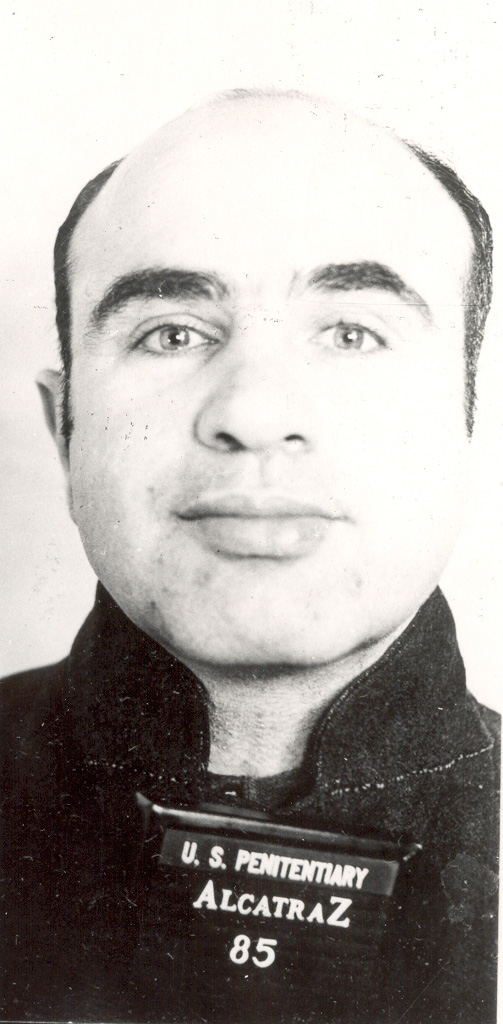 Al Capone facing the camera in an Alcatraz prison mugshot, with penitentiary identification placard.